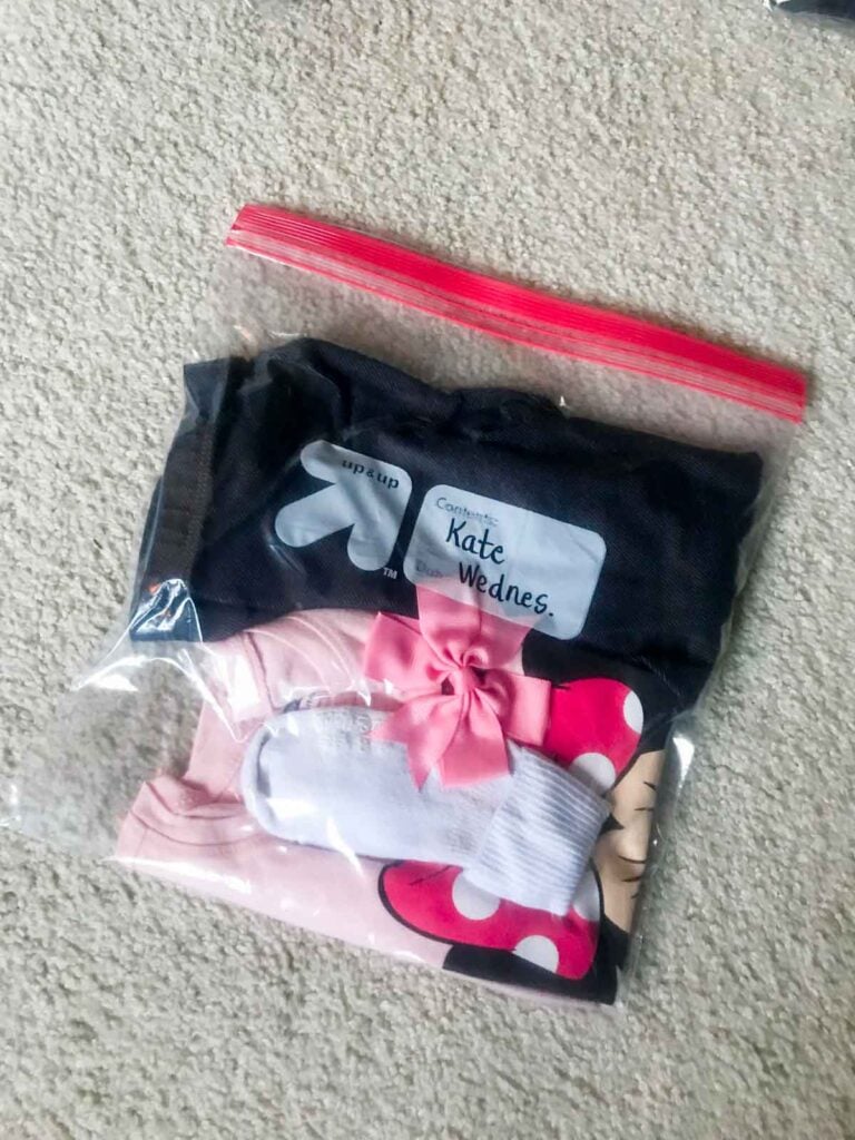 A child's outfit is loaded into a zipper bag.