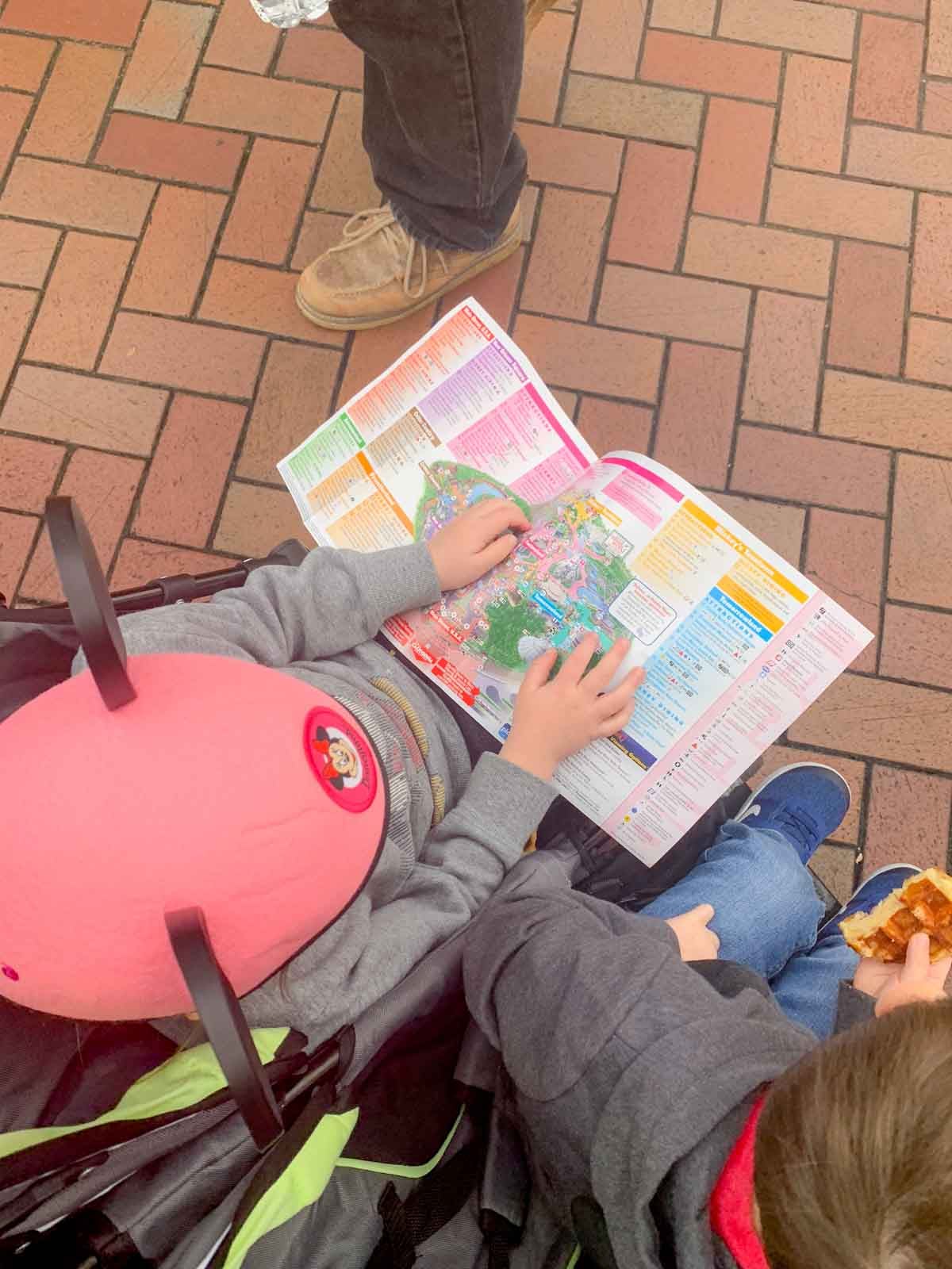 A child in a stroller has a map of Disneyland on her lap.