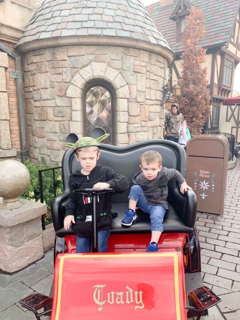 Two kids sit in the Mr Toad's wild ride cart at disneyland.