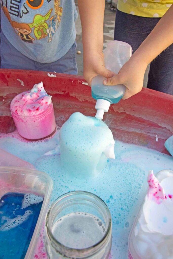 A child squeezes vinegar into a jar of "potions" aka baking soda and soap.