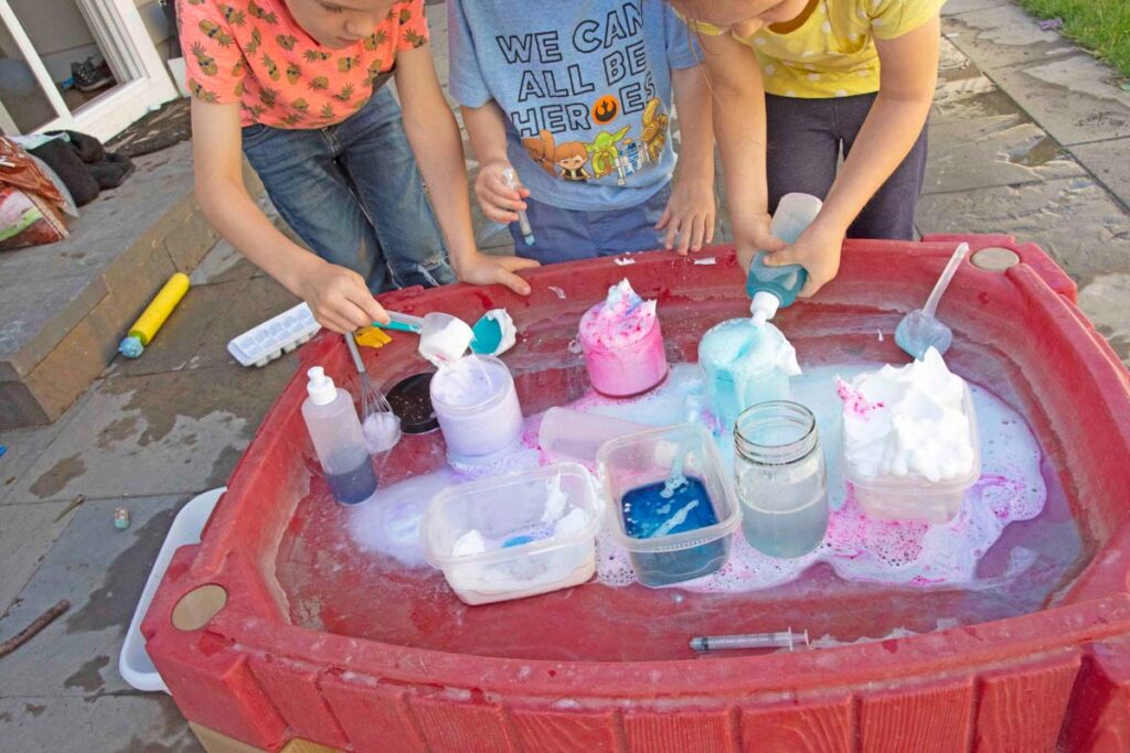 A child squeezes vinegar into a jar of "potions" aka baking soda and soap.