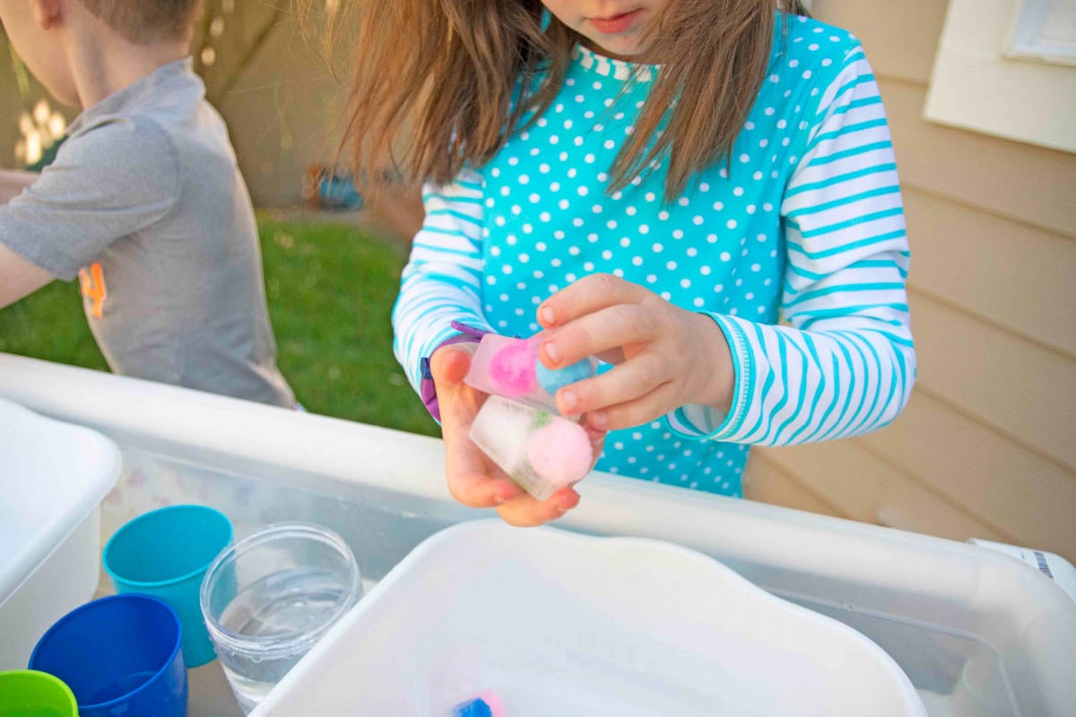 A child holds a collection of frozen pom pom balls.