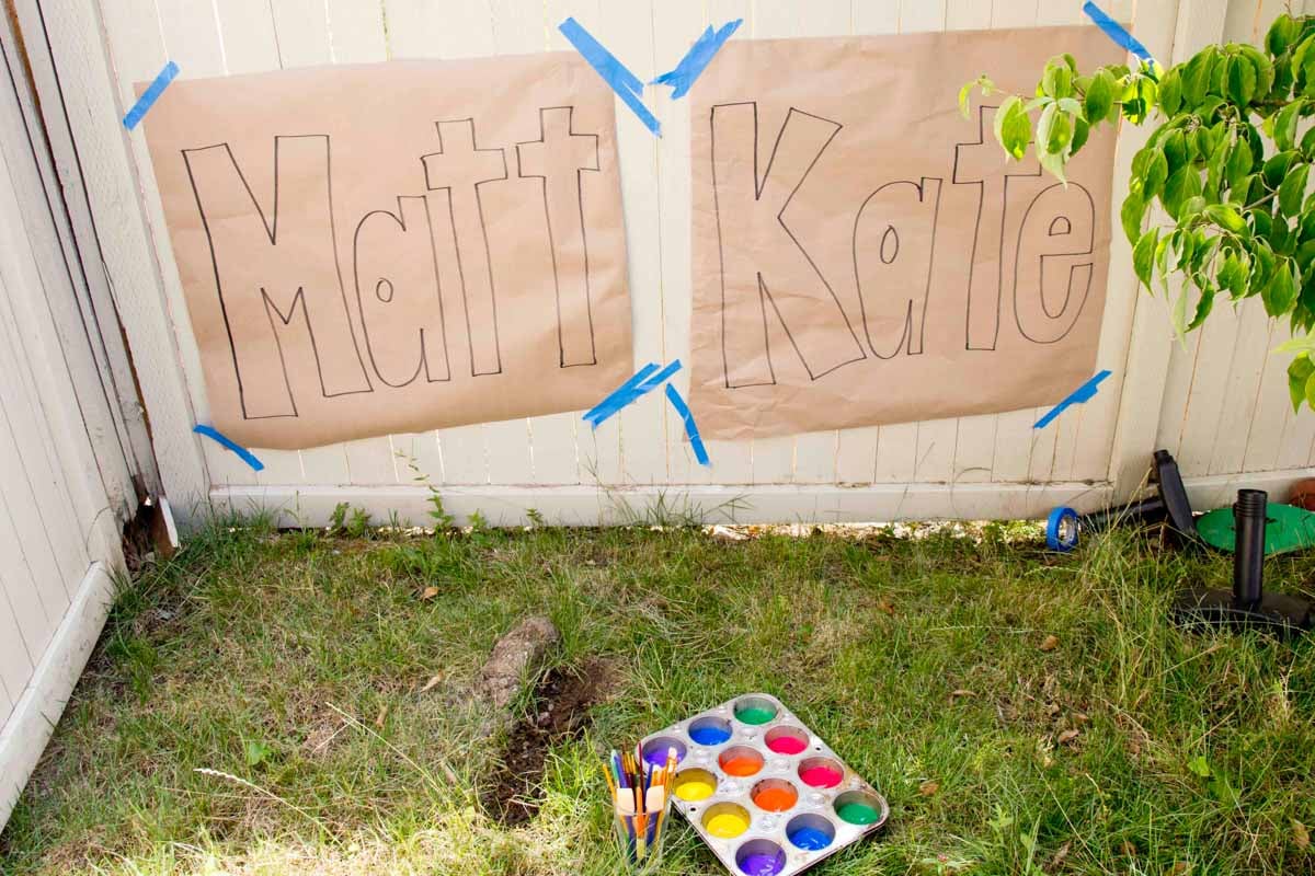 The names MATT and KATE in block letters hang on a fence waiting to be painted.