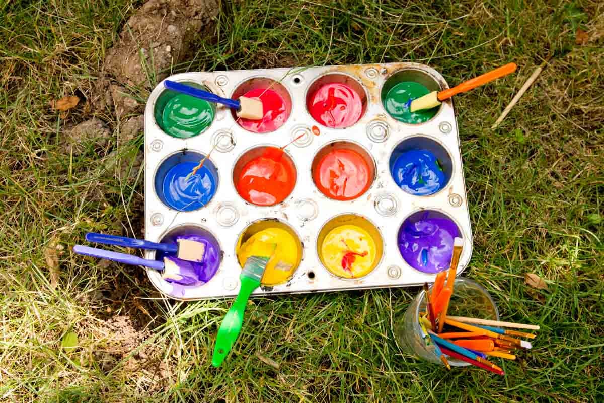 Paint in a muffin tin sits on the grass
