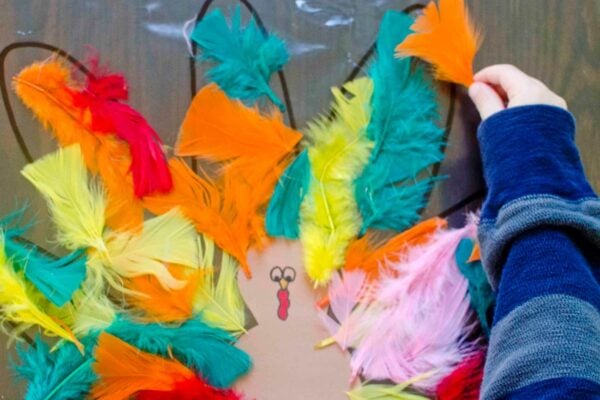 A child places a feather onto a con-tact paper turkey