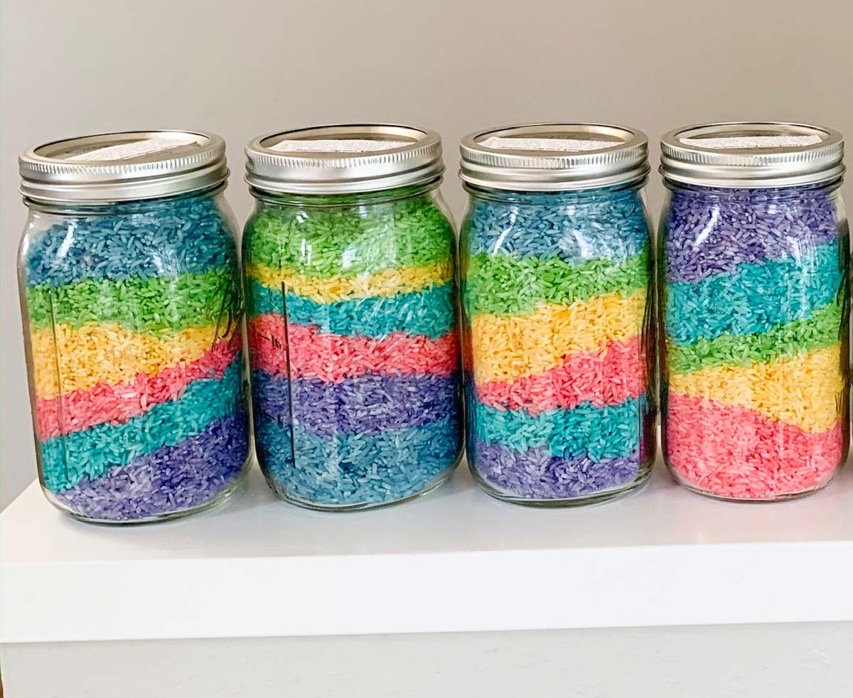 Jars of rainbow rice sit on a railing.