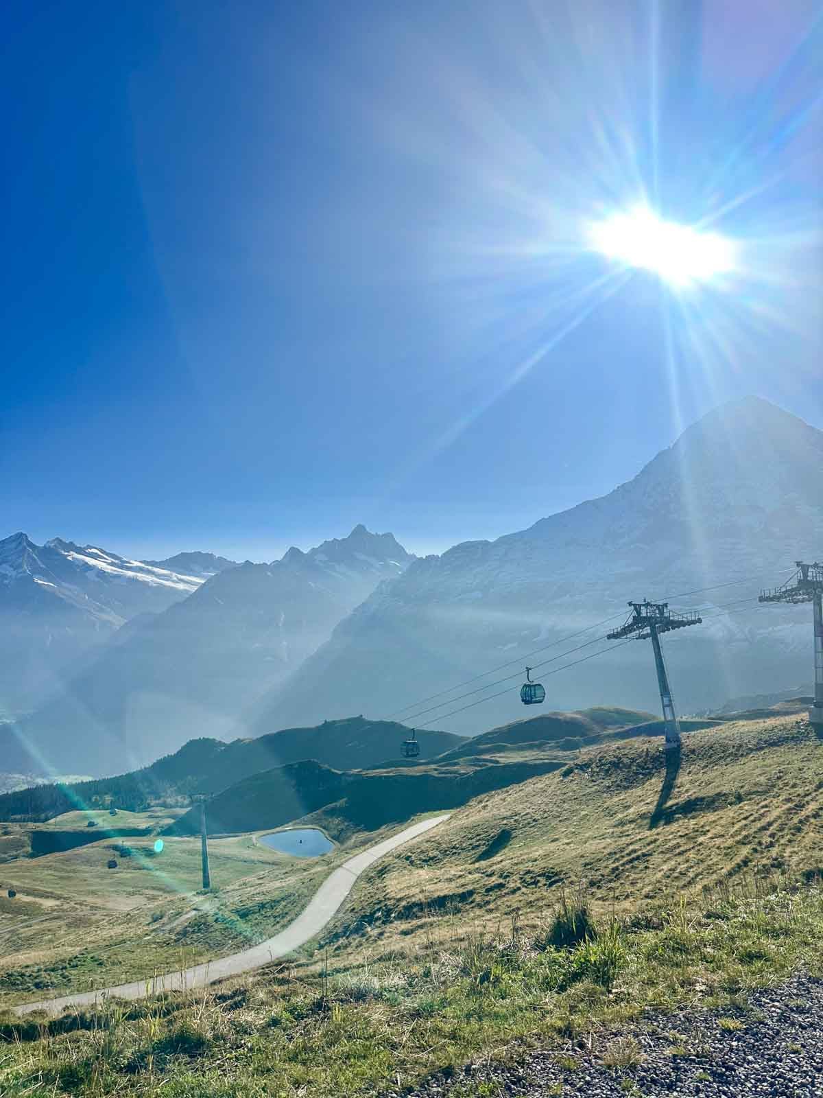 A look at the Swiss Alps with a valley in the front, mountain behind and a gondola swinging downhill.