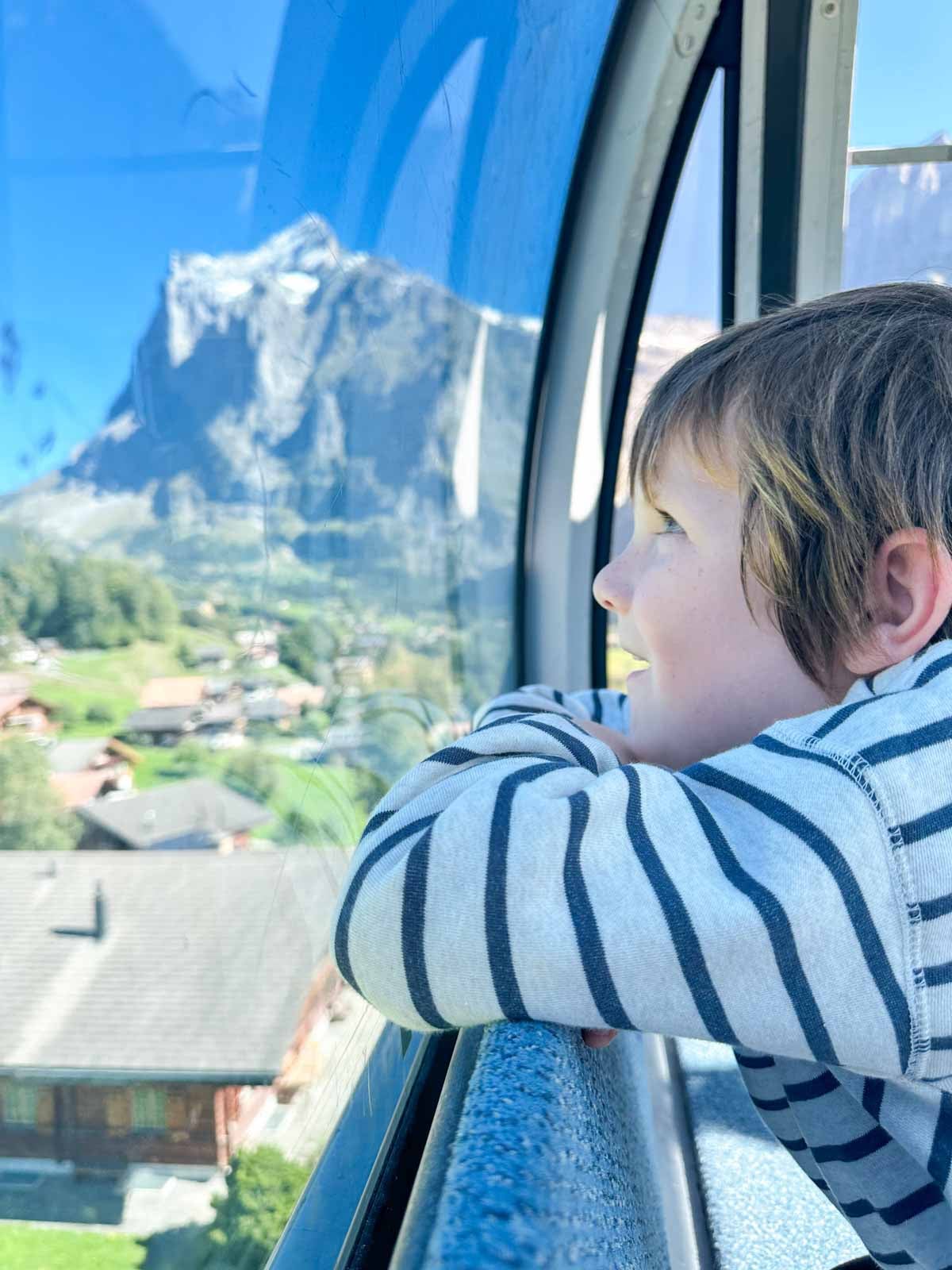 A child looks out the window of a gondola.