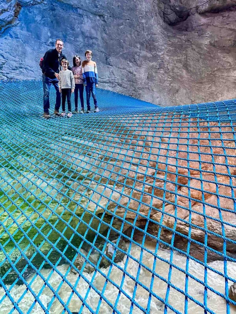 A family on a spider web net over a river.