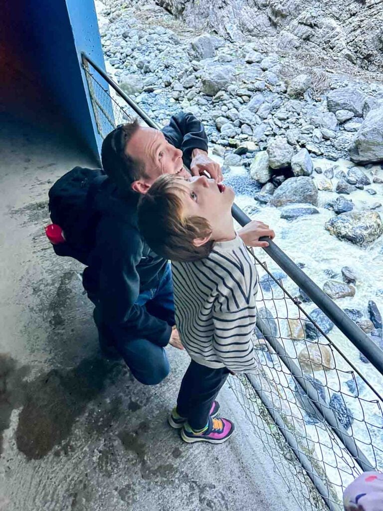 A father and son look up at a waterfall.