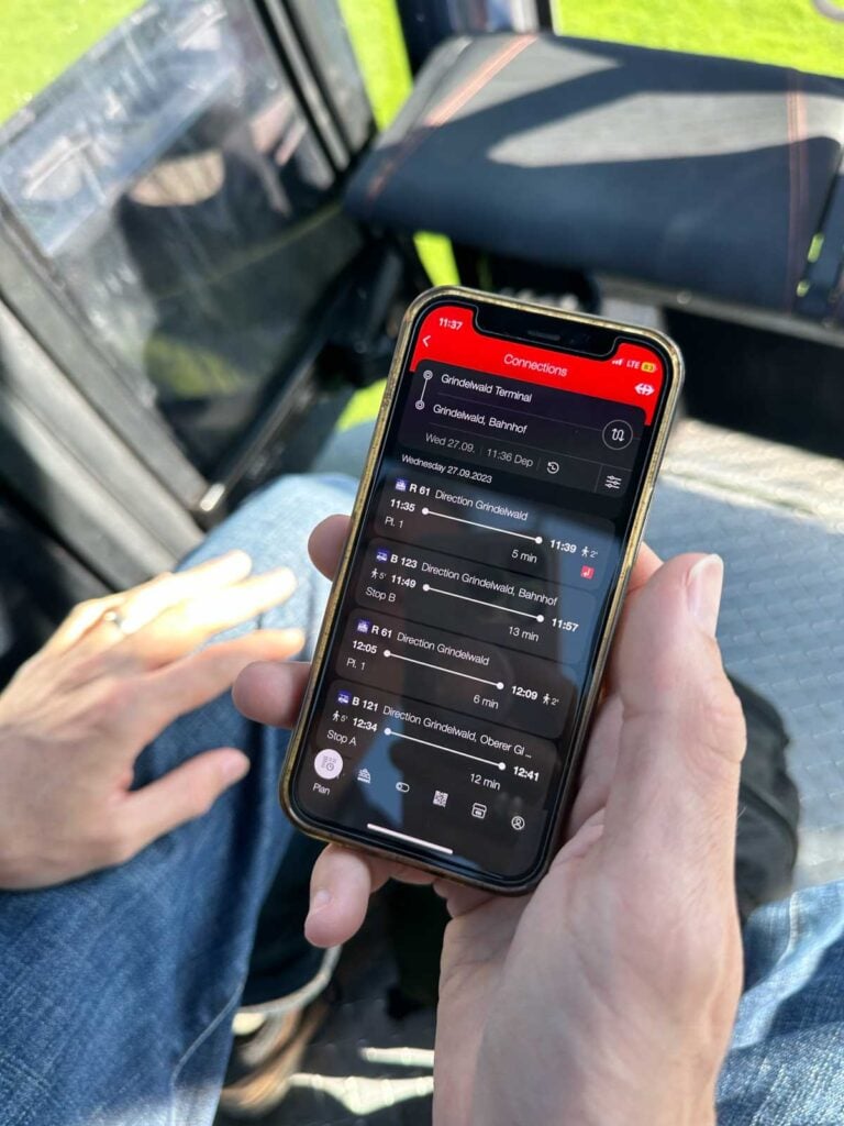 A man's hand holds a phone showing a travel app.