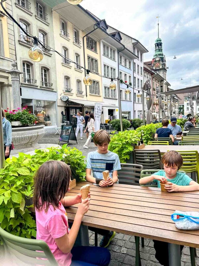 Three children eat ice cream in old town Lenzburg.