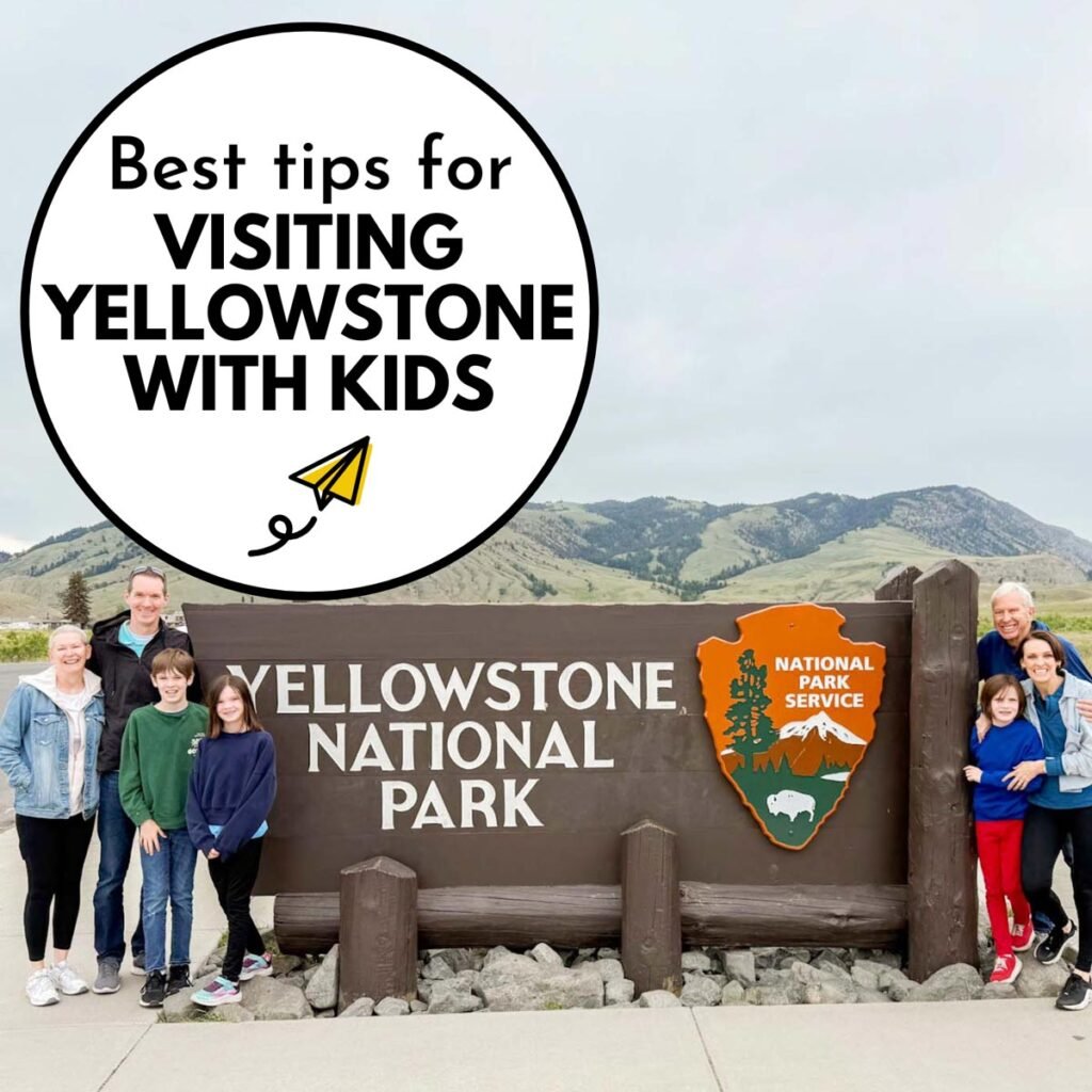 Best tips for Visiting Yellowstone with Kids - a family with grandparents stands at the iconic Yellowstone National Park entrance.