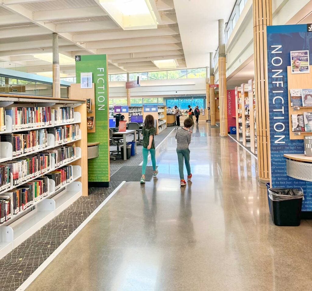 Two elementary children walk through a library without an adult
