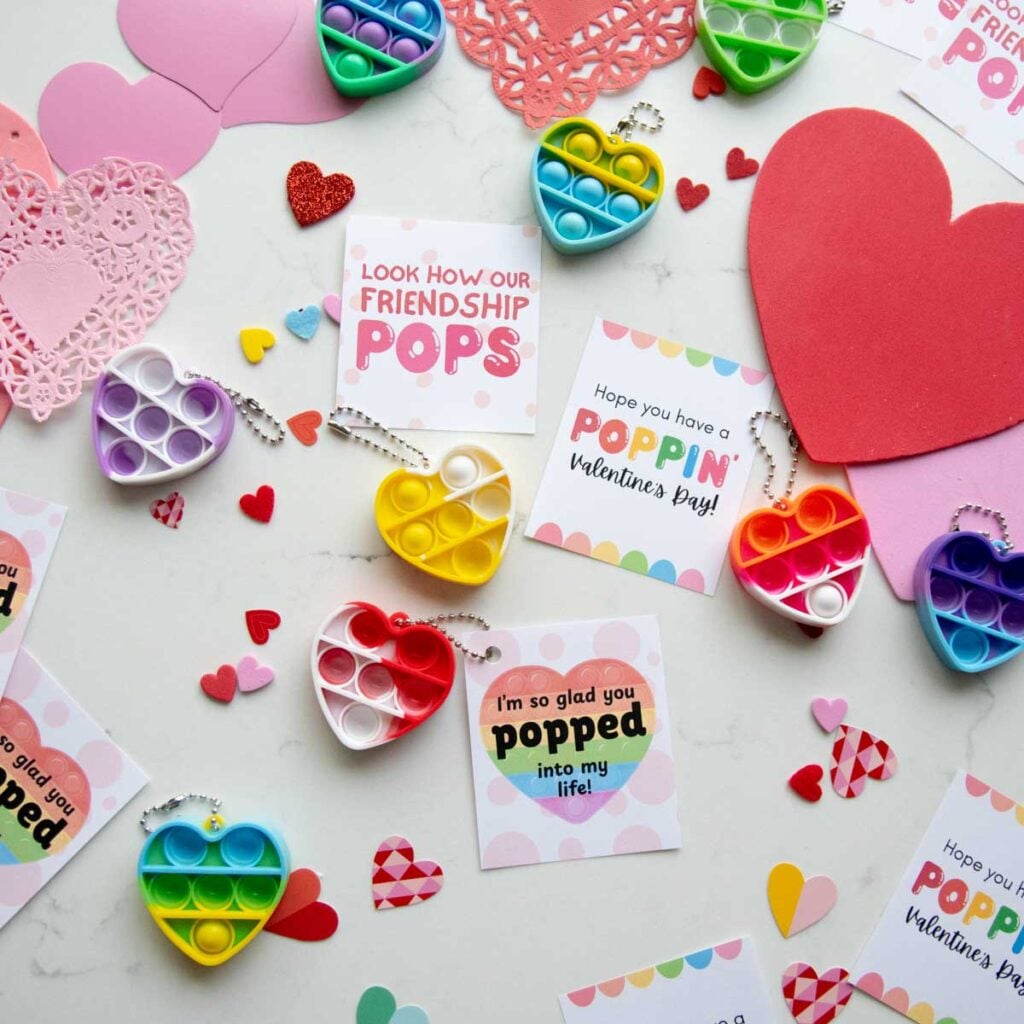 A flat lay of Valentine's day cards and hearts with pop fidget key chains. The Valentines are all puns around the word "pop."