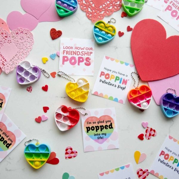 A flat lay of Valentine's day cards and hearts with pop fidget key chains. The Valentines are all puns around the word "pop."