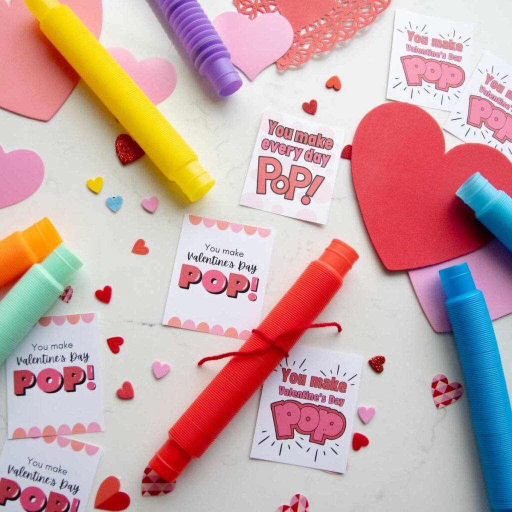 A flat lay for Valentine's day cards. There are three styles of Valentine's day card set amongst pop tubes and heart decorations.