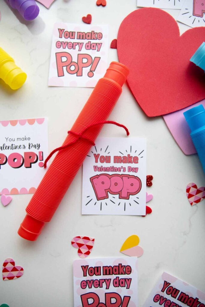 A flat lay for Valentine's day cards. There are three styles of Valentine's day card set amongst pop tubes and heart decorations.