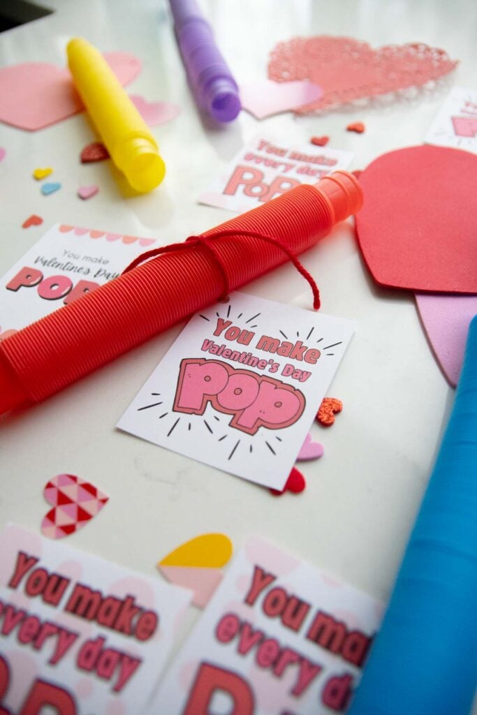 A flat lay for Valentine's day cards. There are three styles of Valentine's day card set amongst pop tubes and heart decorations.