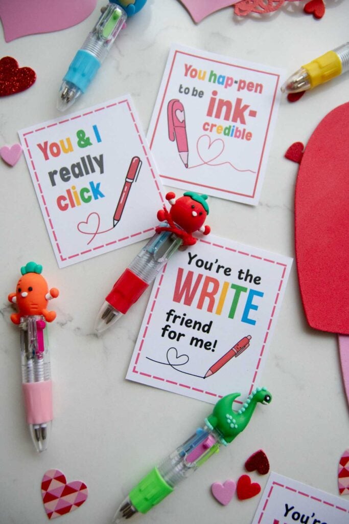 A flat lay on a white counter of Valentines with "write" puns. The treat is a fun multi ink mini pen.