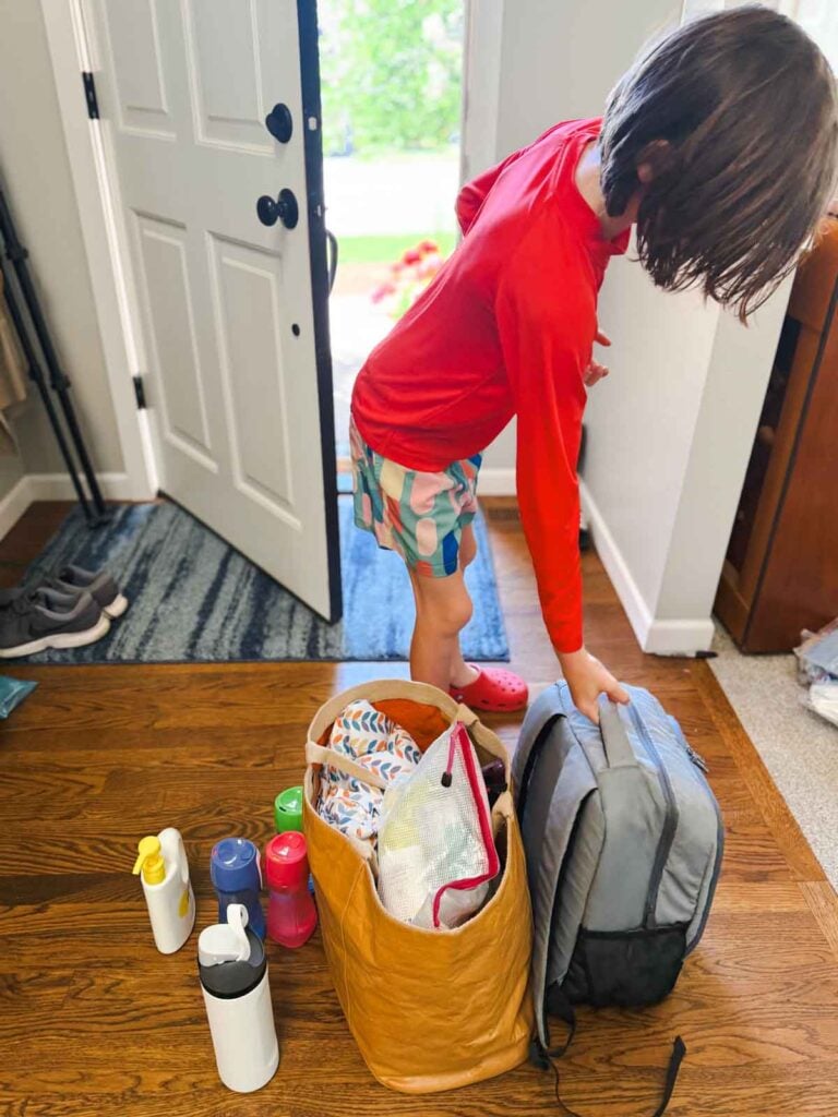 A child reaching for a bags at the front door of a home.